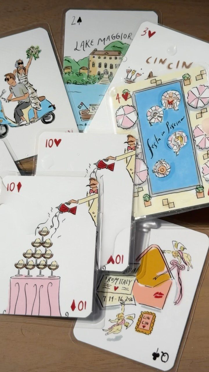 Custom illustrated playing cards with colorful drawings scattered on a wooden table surface.