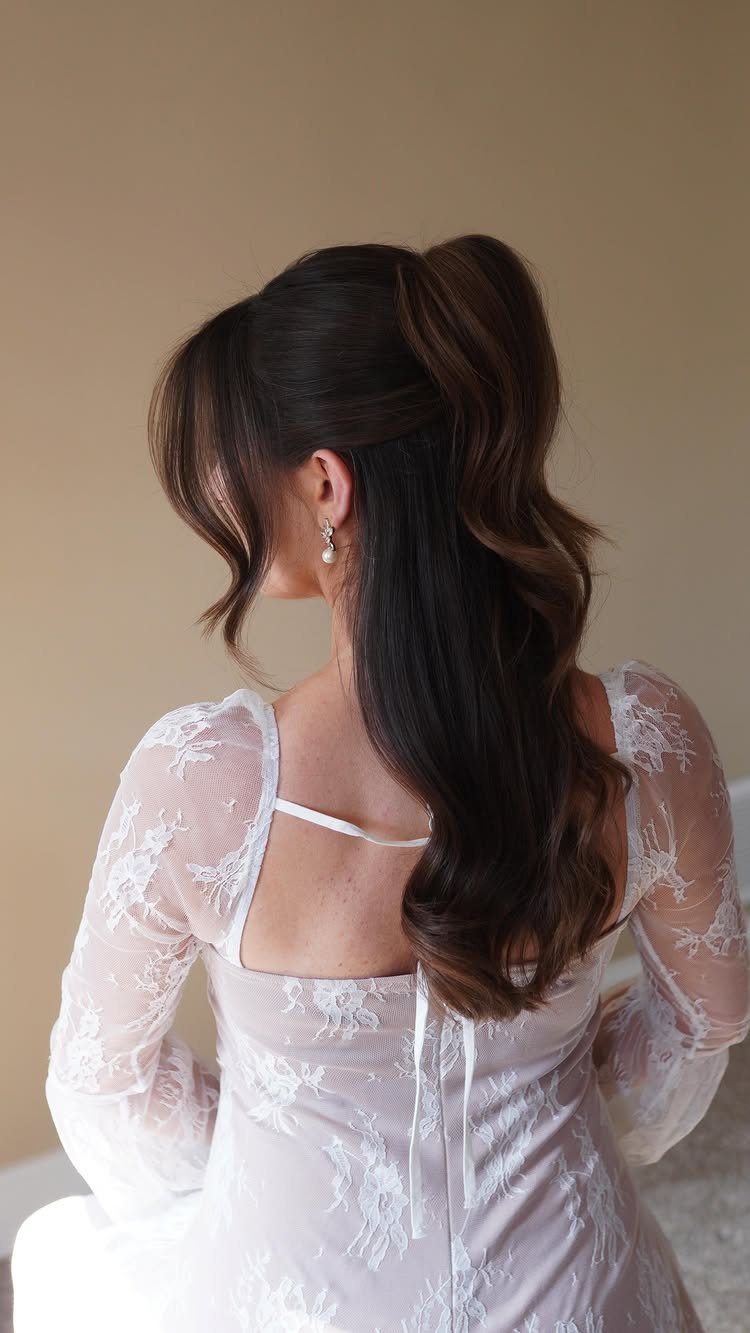 Woman with long dark hair styled in a half up half down wavy wedding hairstyle.