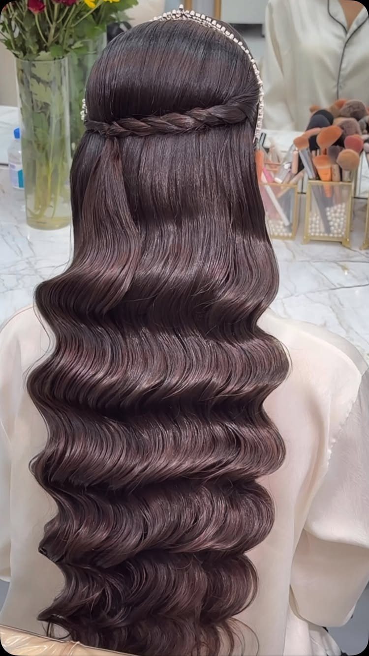 Long dark brown hair styled in deep, glossy waves with a horizontal braid.
