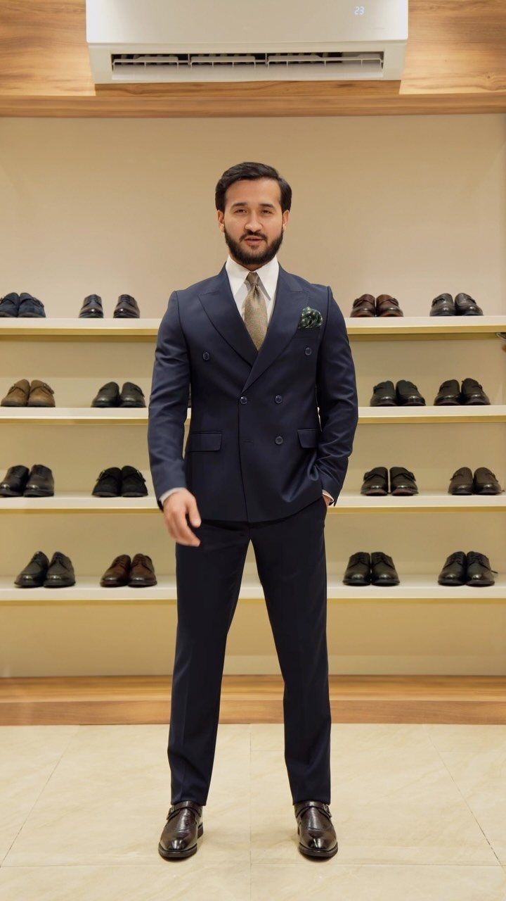 Wedding Suits for Men: 12 Groom Looks Outside Black Tie 7 A man in a navy blue double-breasted suit posing in a shoe store.