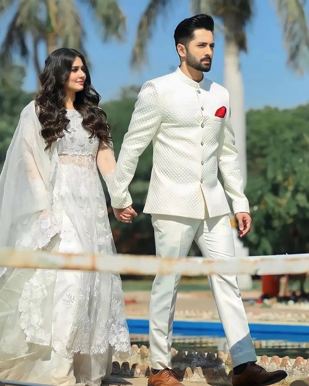 Wedding Suits for Men: 12 Groom Looks Outside Black Tie 10 A man in a white textured suit walking hand-in-hand with a woman in white lace.