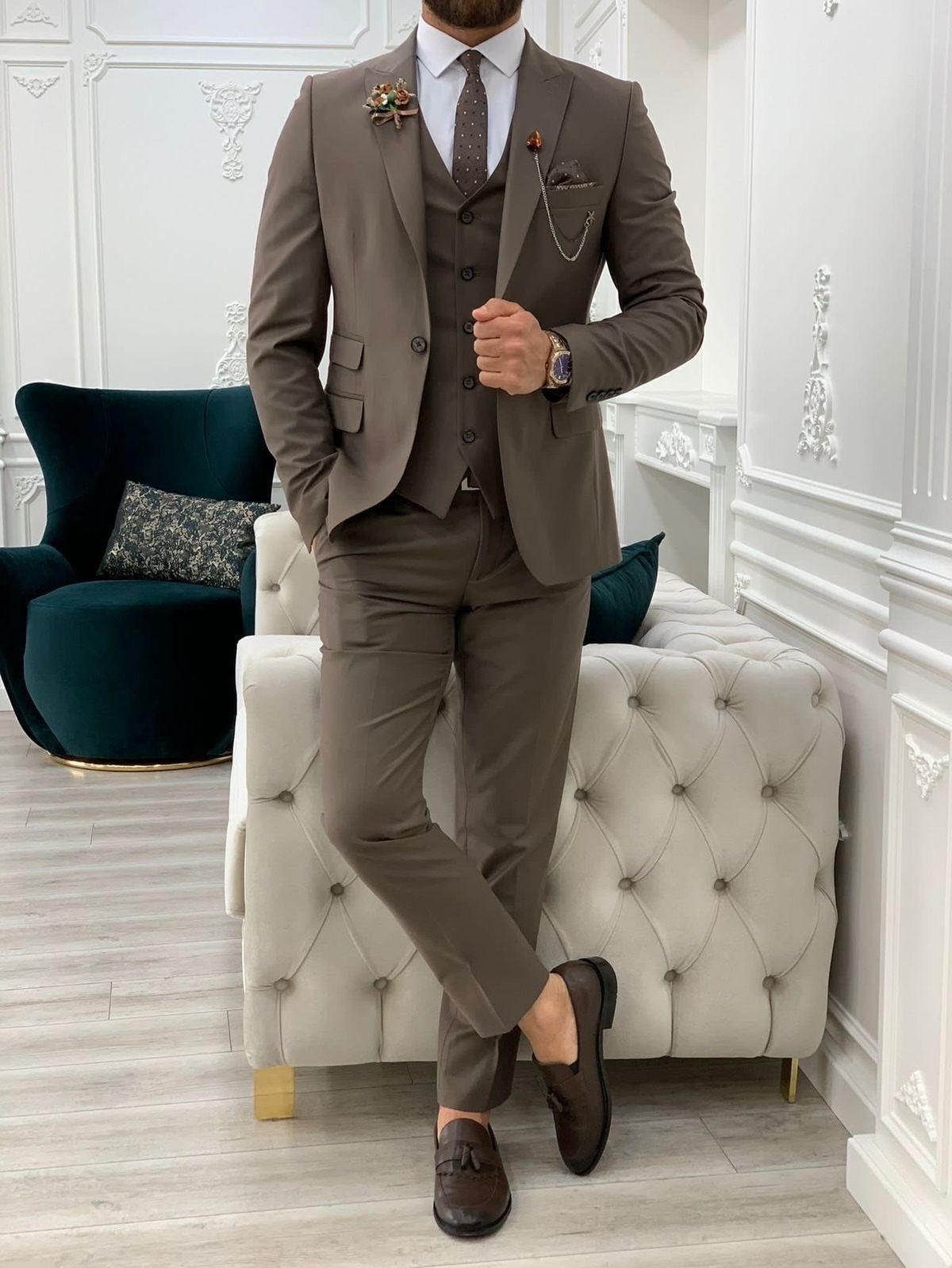 Wedding Suits for Men: 12 Groom Looks Outside Black Tie 5 Man in a tailored brown three-piece suit posing in a bright, elegant room.