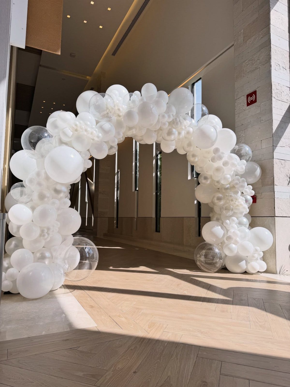 White Wedding Decorations: 10 Ideas for an Elegant Celebration 2 A large organic archway made of white and translucent balloons at a building entrance.