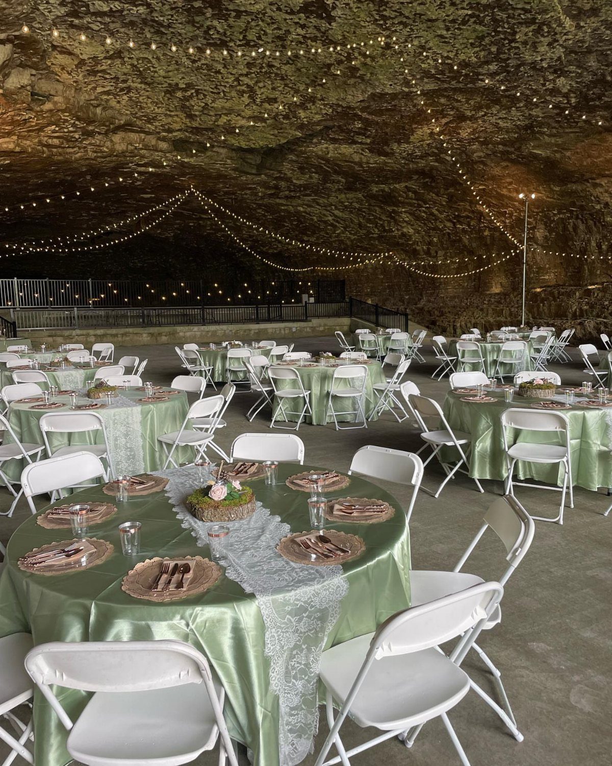 White Wedding Decorations: 10 Ideas for an Elegant Celebration 10 Round tables with green satin cloths and white lace runners set inside a large decorated cave.