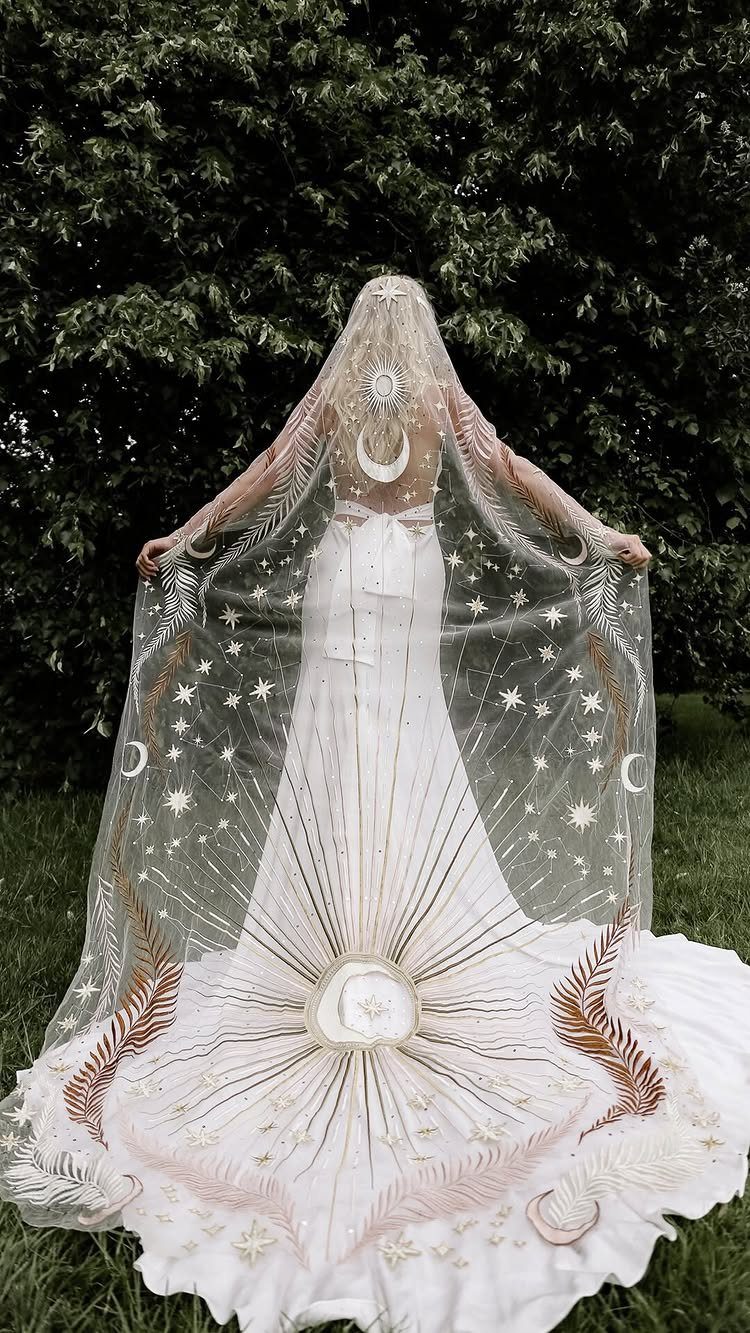 7 Enchanting Ideas for Witchy Wedding Dresses 7 A person wearing a cream slip dress and a celestial patterned veil with stars and moons.