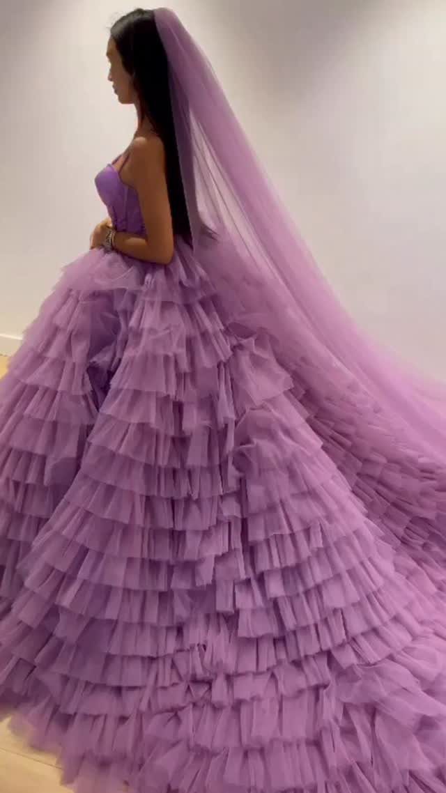 7 Enchanting Ideas for Witchy Wedding Dresses 3 A woman wearing a voluminous tiered purple tulle wedding gown and a long matching veil.